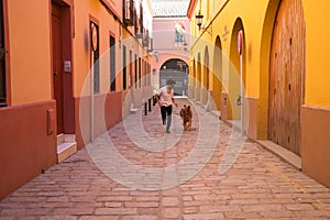 handsome, young Hispanic man with his brown golden retriever dog, running through the streets of a European city while having fun