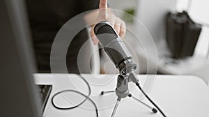 Handsome young hispanic man, a passionate reporter testing mic inside bustling radio studio, preparing to broadcast live news on