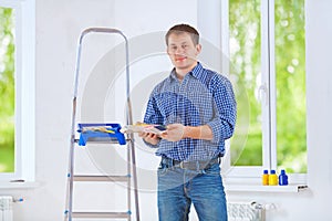 Handsome young homeowner holding color palette and looking at ca