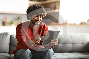 Handsome young indian guy using digital tablet at home