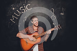 Handsome young instrumentalist playing on the guitar and singer photo