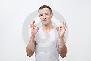 A handsome young italian man in gray t-shirt showing ok sign