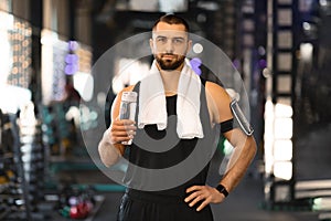 Handsome Young Male Athlete With Water Bottle In Hands Posing At Gym