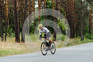 Handsome young male cyclist trains outside the city in the woods on the road. Riding a bike