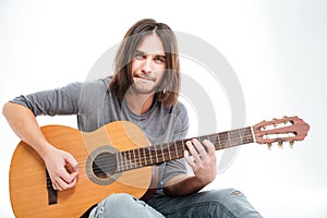 Handsome young male guitarist sitting and playing acoustic guitar