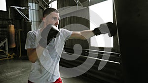 Handsome young male training with punching bag in the gym. Hardworking boxer effectively working on her punches with