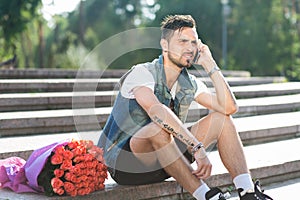 Handsome young male waiting for his girlfriend with bouquet roses.