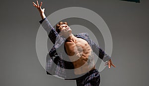 Handsome young man actor and dancer in suit dancing modern expressive dance in studio isolated on gray background