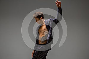 Handsome young man actor and dancer in suit dancing modern expressive dance in studio isolated on gray background