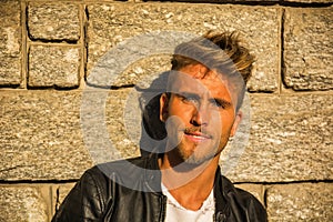 Handsome young man against stone wall, outdoor