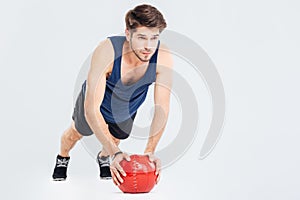 Handsome young man athlete doing push ups on red ball