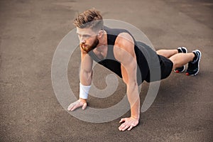 Handsome young man athlete training and doing plank exercise outdoors
