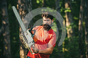 Handsome young man with axe near forest. Deforestation. Lumberjack in the woods with chainsaw axe. Agriculture and