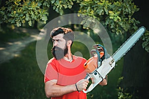 Handsome young man with axe near forest. Stylish young man posing like lumberjack. A handsome young man with a beard