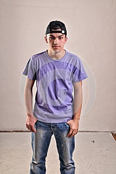 Handsome young man with backwards cap on his head posing in stud