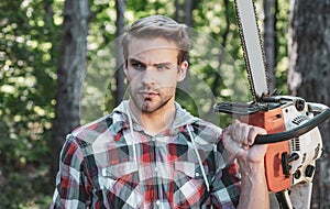 Handsome young man with a beard carries a tree. Woodworkers lumberjack. Firewood as a renewable energy source