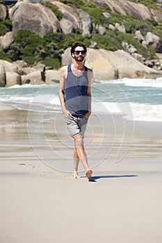 Handsome young man with beard walking on isolated beach