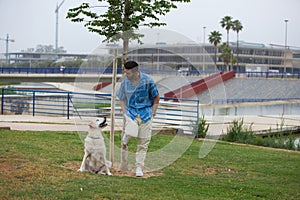 Handsome young man with beard walks with his large dog. The dog is a brown Labrador Retrievier. Concept pets and companion animals