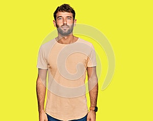 Handsome young man with beard wearing casual tshirt relaxed with serious expression on face