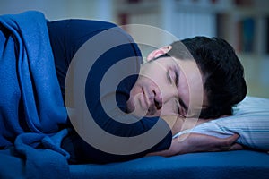 Handsome young man in bed falling asleep after suffering insomnia and sleep disorder