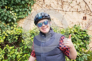 Handsome young man with bicycle showing thumbs up in park on sunny day