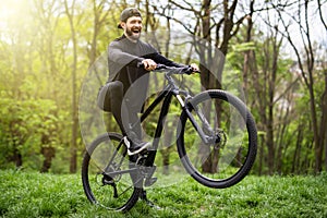Handsome young man biking in the countryside forest