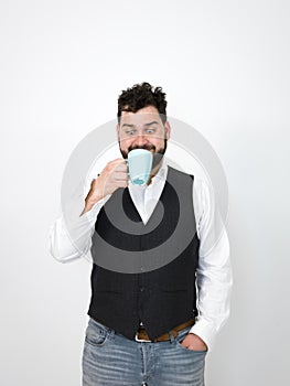 Handsome, young man with black beard posing with turquoise coffee cup or tea cup in front of white background