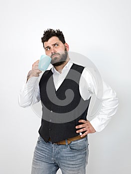 Handsome, young man with black beard posing with turquoise coffee cup or tea cup in front of white background