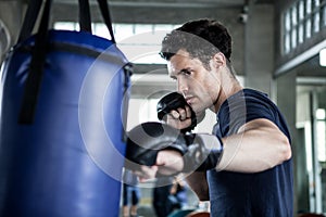 Handsome young man boxer is exercising with a punching bag at training fitness gym.male boxing workout sport