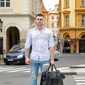 Handsome young man on business trip walking with his luggage on street. Travelling businessman.