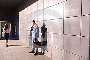 Handsome young man, businessman talking on phone passes by beaut