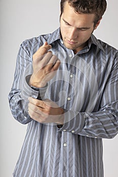 Handsome young man buttoning cuffs of dress shirt. Men`s clothing styles businessman getting ready for work putting on clean