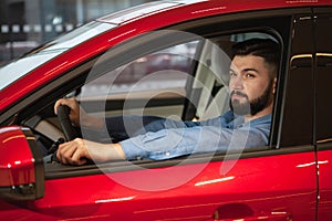 Handsome young man buying new car at the dealership