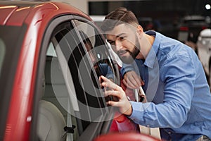 Handsome young man buying new car at the dealership