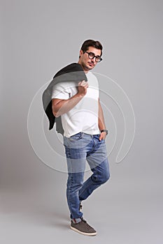 Handsome young man in casual clothes with black jacket and glasses on background