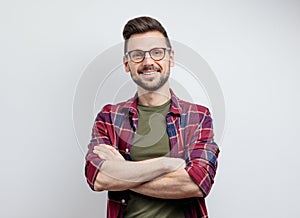 Handsome young man in casual shirt keeping arms crossed and smiling