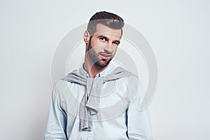Really Handsome young man in casual wear making doubt emotion while standing against grey background