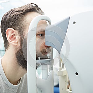 Handsome young man is checking the eye vision in modern ophthalmology clinic. Patient in ophthalmology clinic.