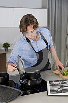 Handsome young man checking a pot at a kitchen