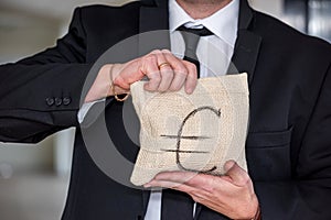 handsome young man in a classic suit with a tie holds in his hands a bag of euros.