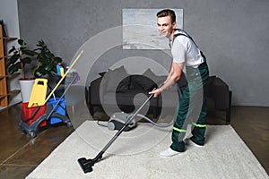 handsome young man cleaning white carpet with vacuum cleaner and smiling