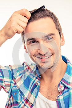 Handsome young man combing his hair