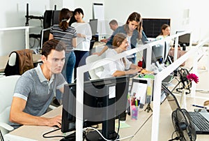 Handsome young man confidently working on computer in modern open plan office