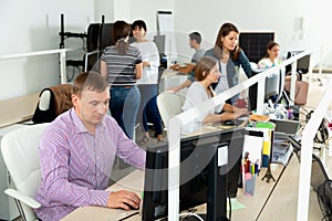 Handsome young man confidently working on computer in modern open plan office