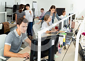 Handsome young man confidently working on computer in modern open plan office