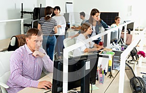 Handsome young man confidently working on computer in modern open plan office