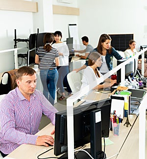 Handsome young man confidently working on computer in modern open plan office