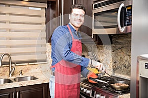 Handsome young man cooking breakfast at home