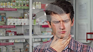 Handsome young man coughing having sore throat standing at the pharmacy