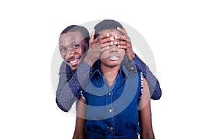 Handsome young man covering his wife`s eyes with his hands smiling